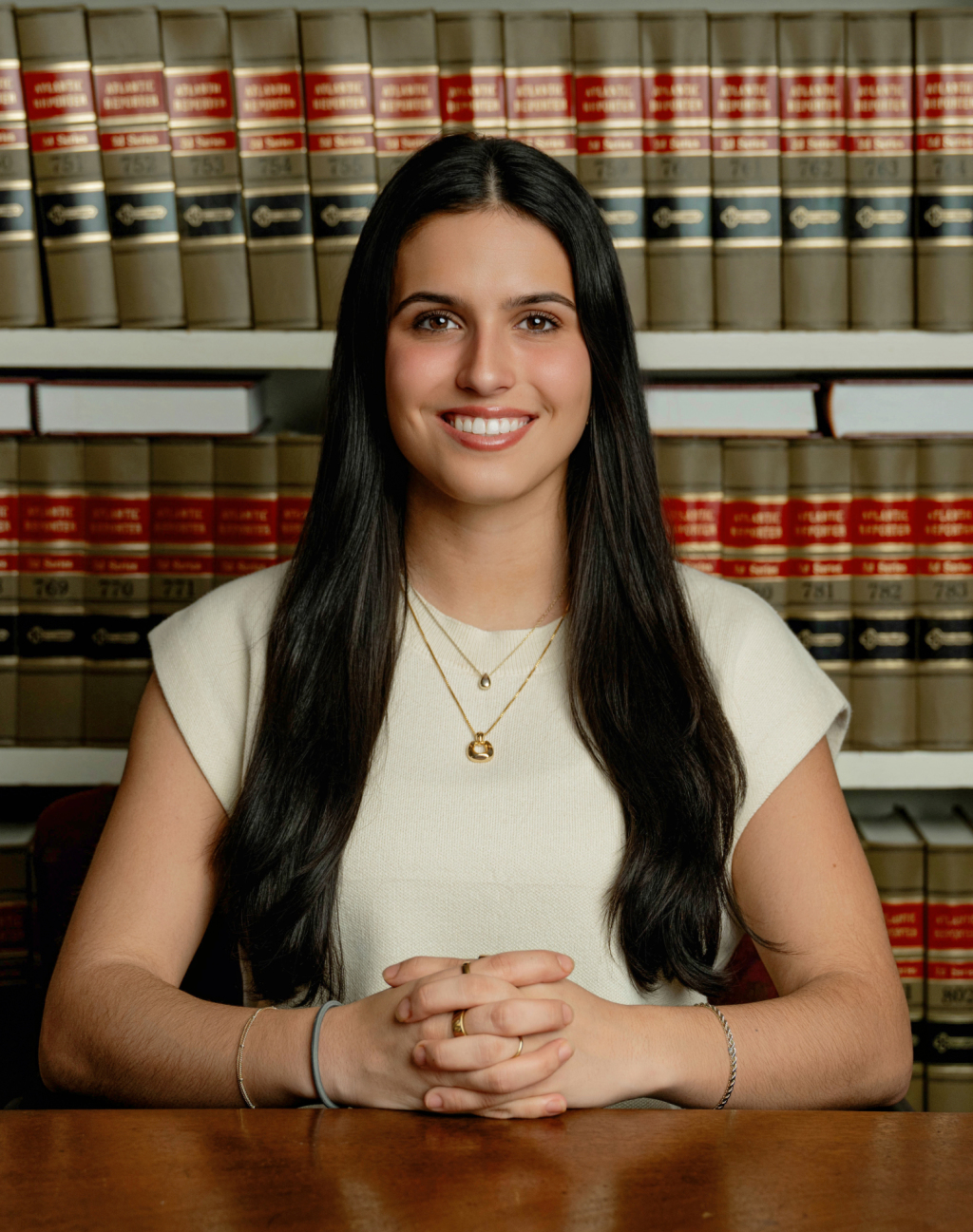 Portrait of Personal Injury Paralegal Zen Price smiling in front of a case of legal books.