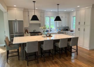 Open-concept kitchen remodel in Chester County with custom white cabinetry, white oak floors, and a large central island designed by DMB Contracting.