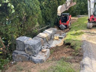 Base preparation and gravel compaction before setting natural stone boulders in West Chester, PA