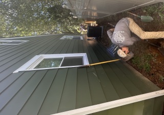 One Thousand Hands Horticulture crew member hand digging a drainage trench between a house and fence