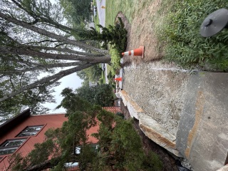 Exposed gravel walkway base bordered by large boulders and existing garden plantings