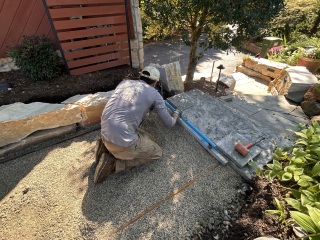 Crew member using a level to check a large natural stone step during installation
