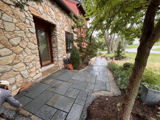 Dimensional bluestone paving forming a wider landing outside the front door of a stone house