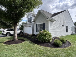 Refreshed foundation garden in Media PA with shrubs, smaller new plants, dark mulch, and curved bed edges