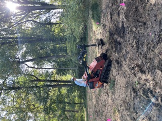 Ditch Witch SK800 with an auger attachment among pink flags marking locations in a meadow