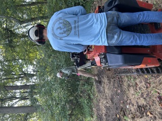 One Thousand Hands Horticulture crew member operating a tracked machine beside a worker with a shovel