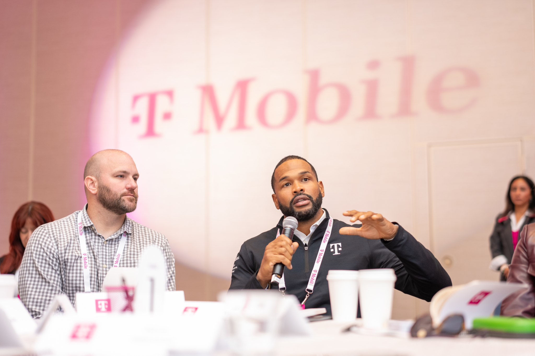 Participant speaking into a microphone with the T-Mobile logo projected behind him at the Leadership Institute in Washington, DC.