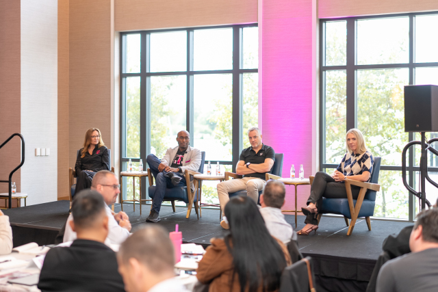 Four panelists seated on stage during a leadership discussion, viewed from the audience.
