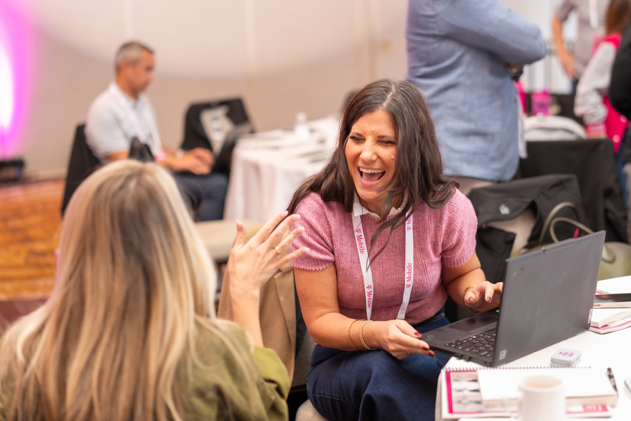 Attendee laughing with another participant during a conversation beside her laptop.